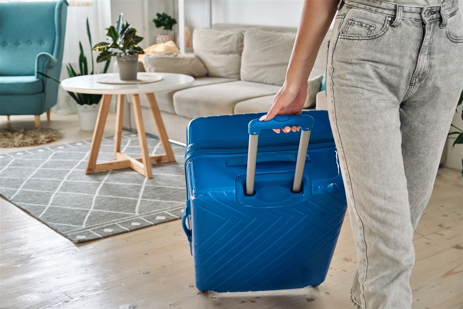 Gast rollt einen blauen Koffer in ein möbliertes Apartment