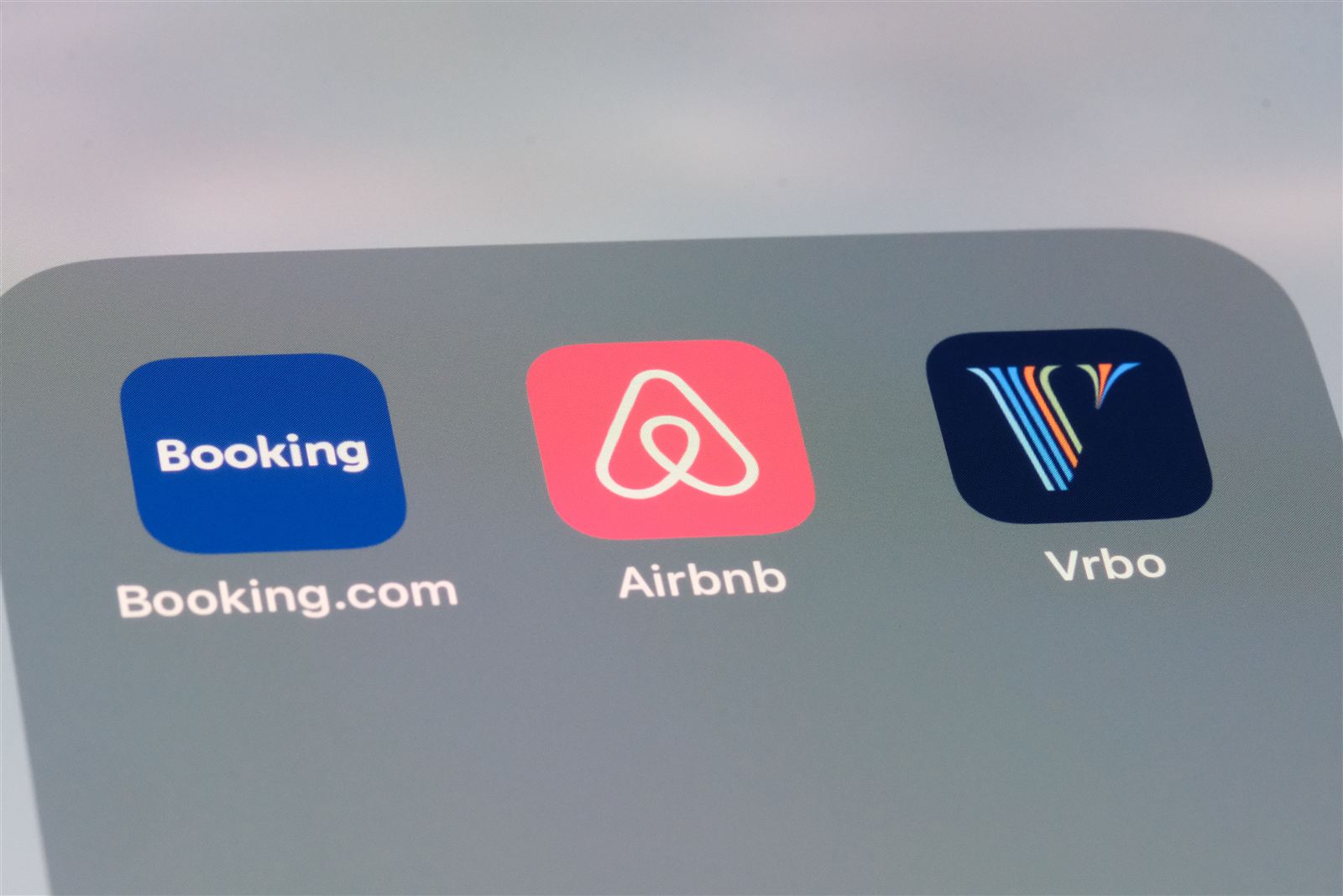 App-Symbole von Booking.com, Airbnb und Vrbo auf einem Smartphone