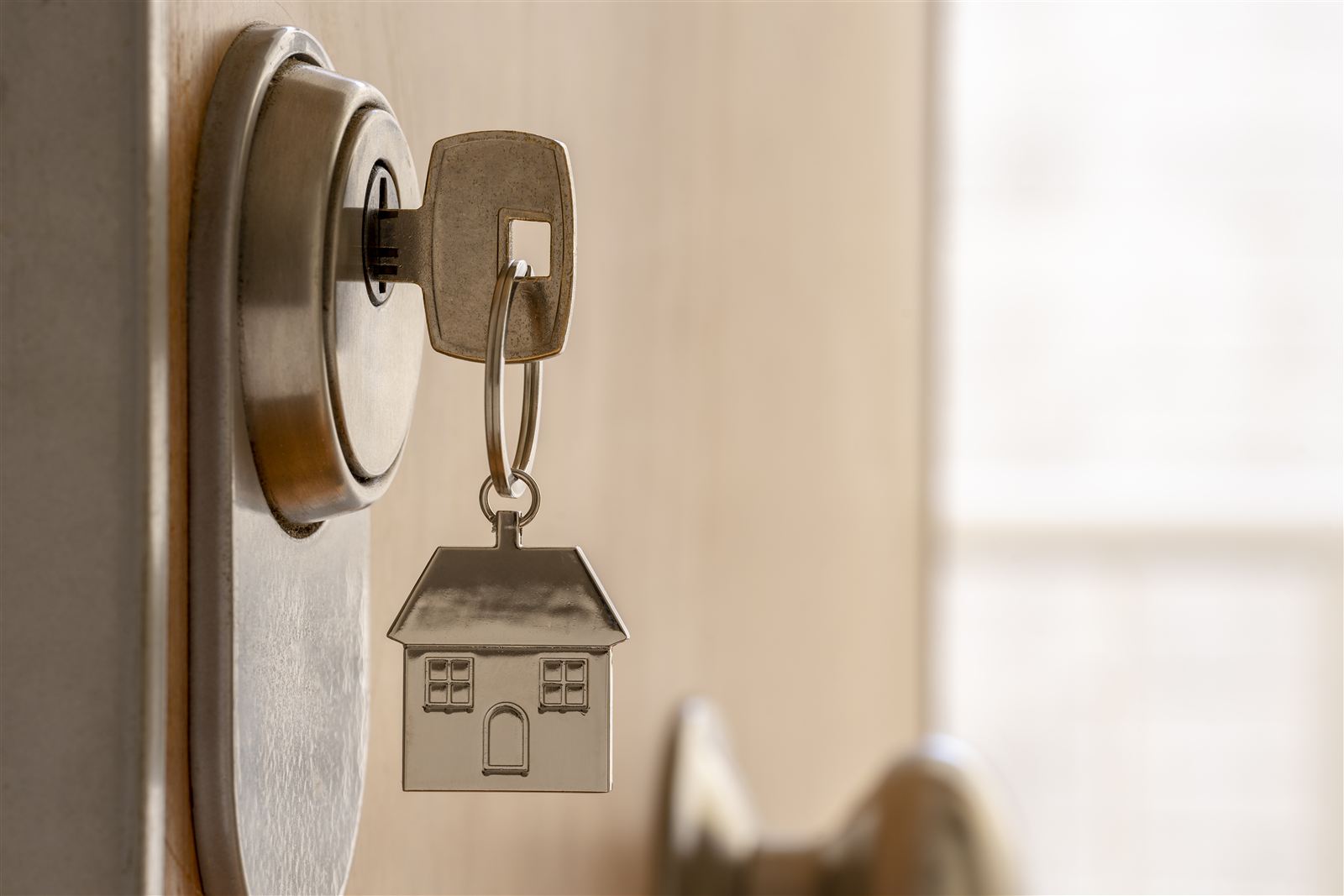 Schlüssel mit Haus-Anhänger steckt in einer Wohnungstür